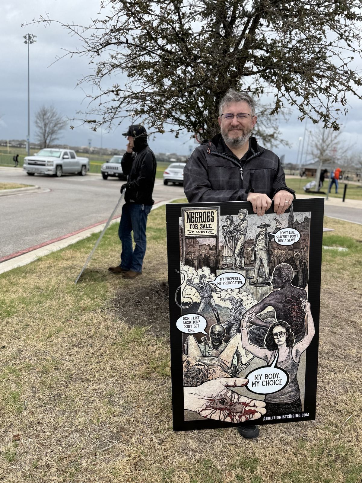 A man holding a sign comparing abortion to the slave auction