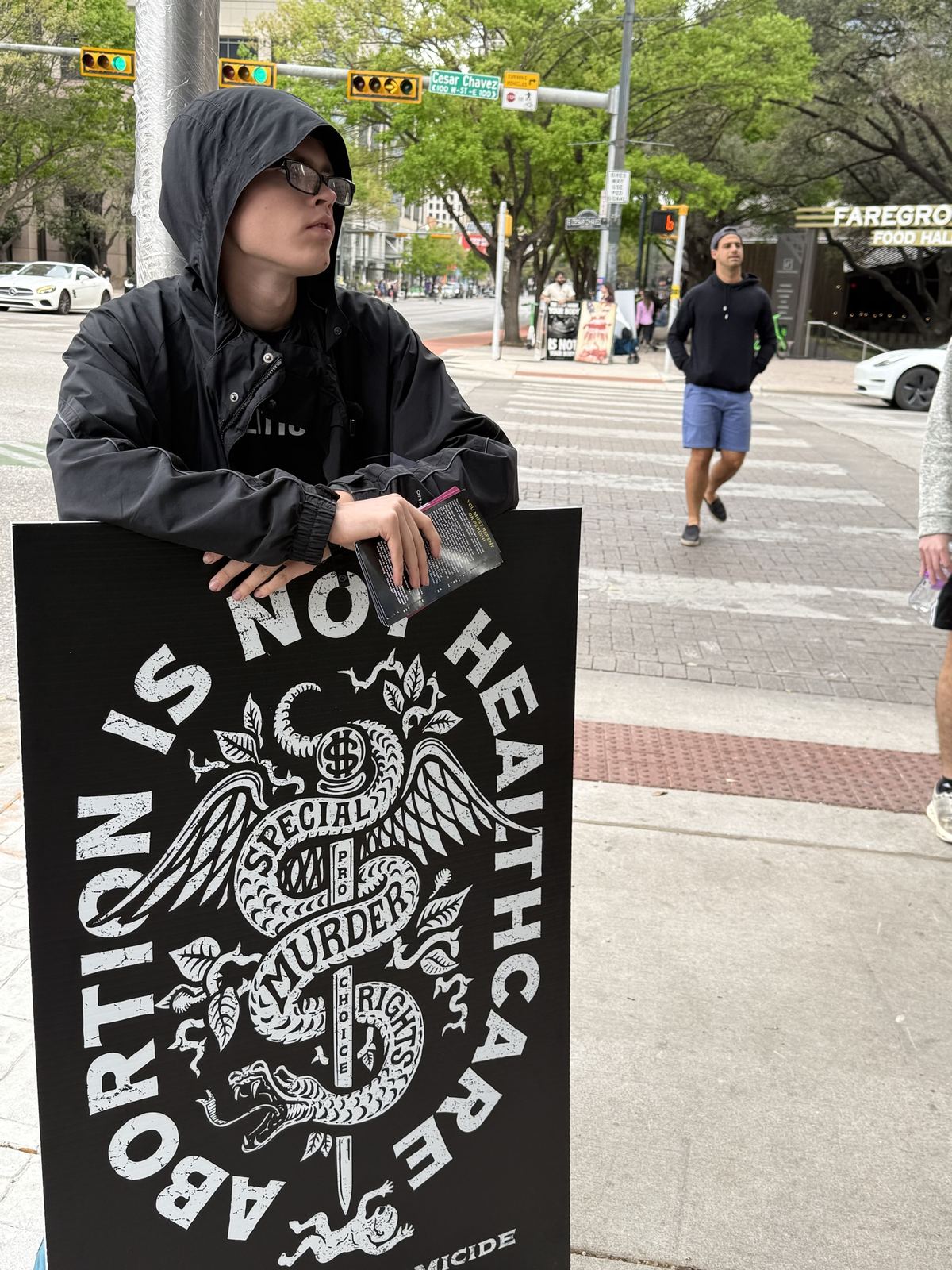 A young man leaning on a sign that says abortion is not healthcare