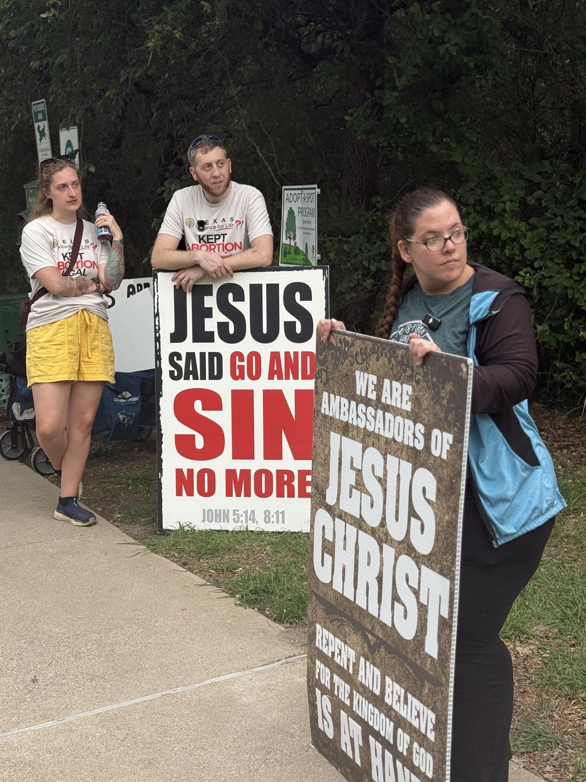 Three people with signs quoting Jesus on repentance and ambassadors of Christ