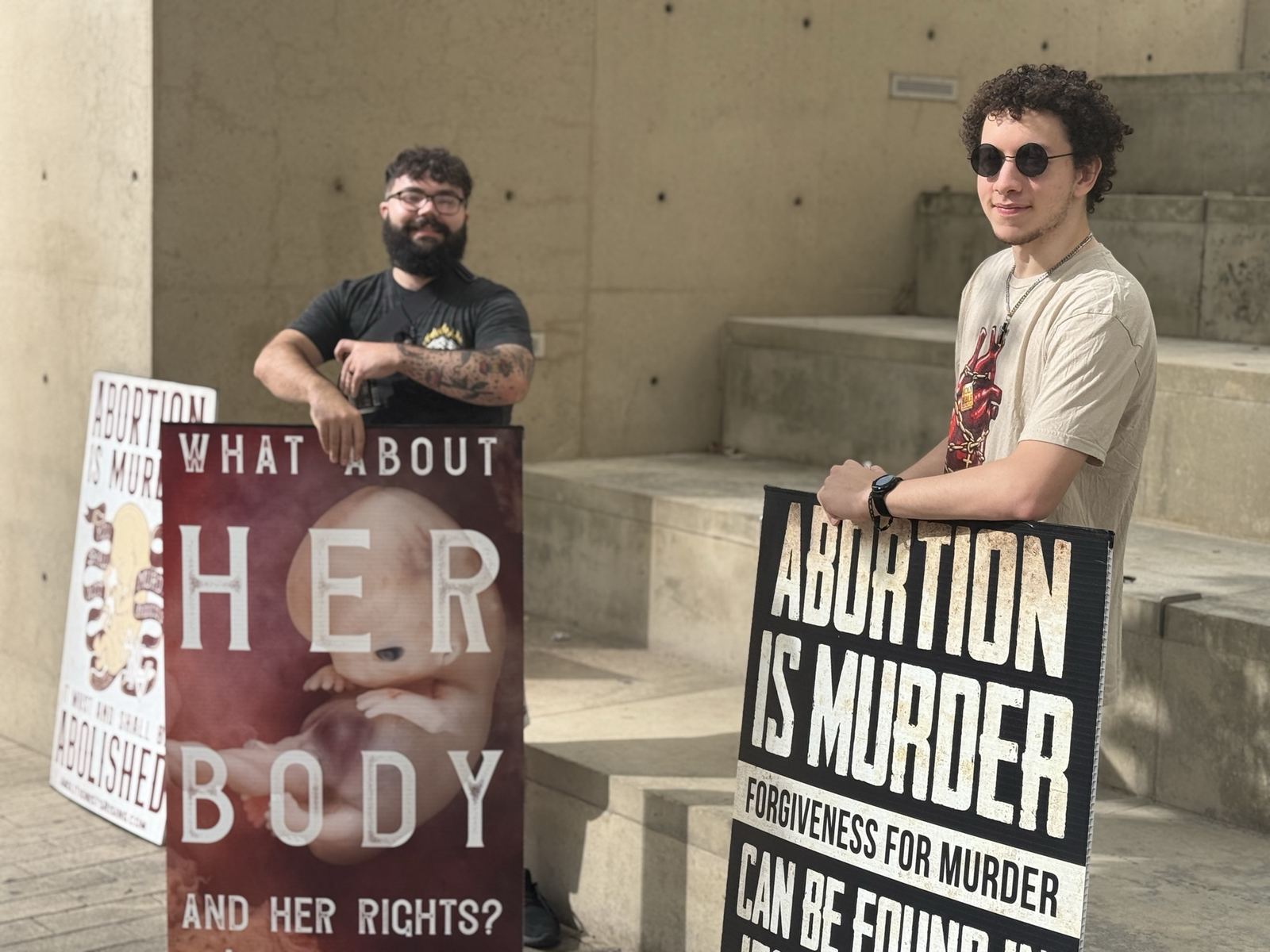 Two abolitionists with signs on concrete steps