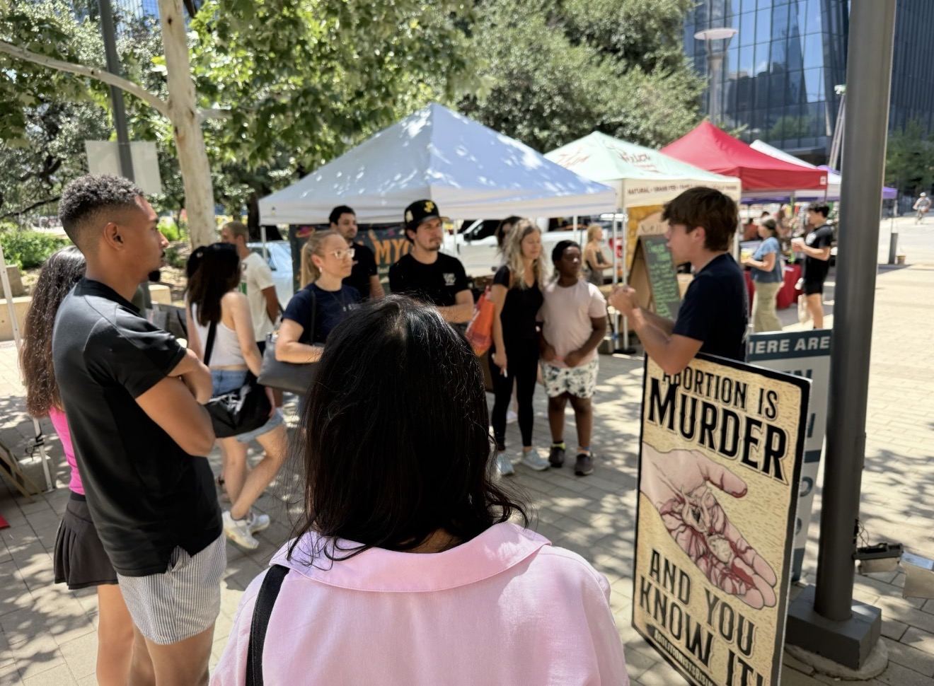 A group listening to an abolitionist beside an abortion is murder sign