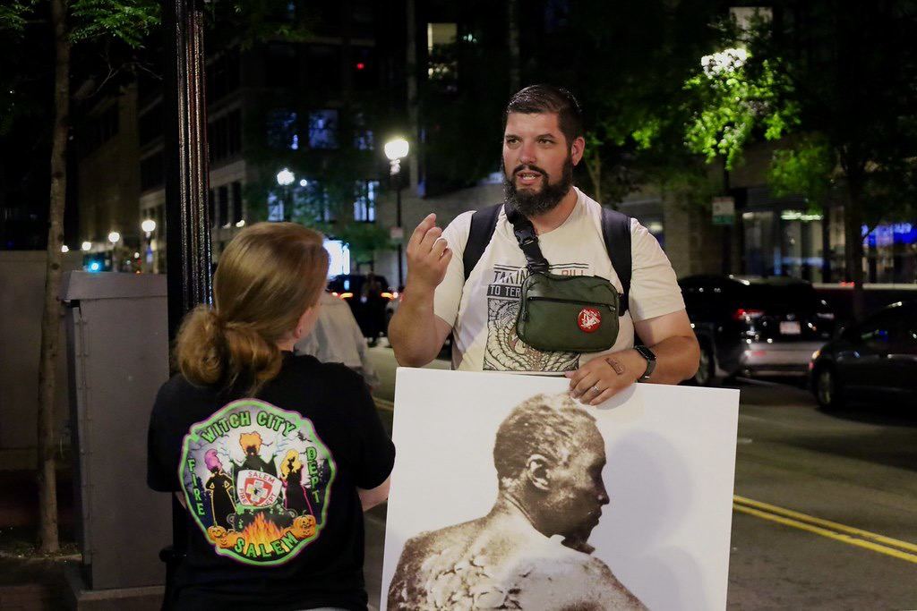 A nighttime conversation beside a sign on a city street