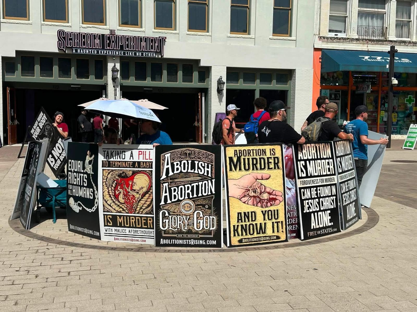 Abolitionists holding a row of signs on a downtown plaza