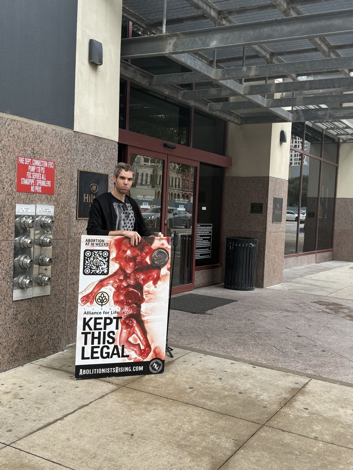 A man with a sign outside a hotel entrance